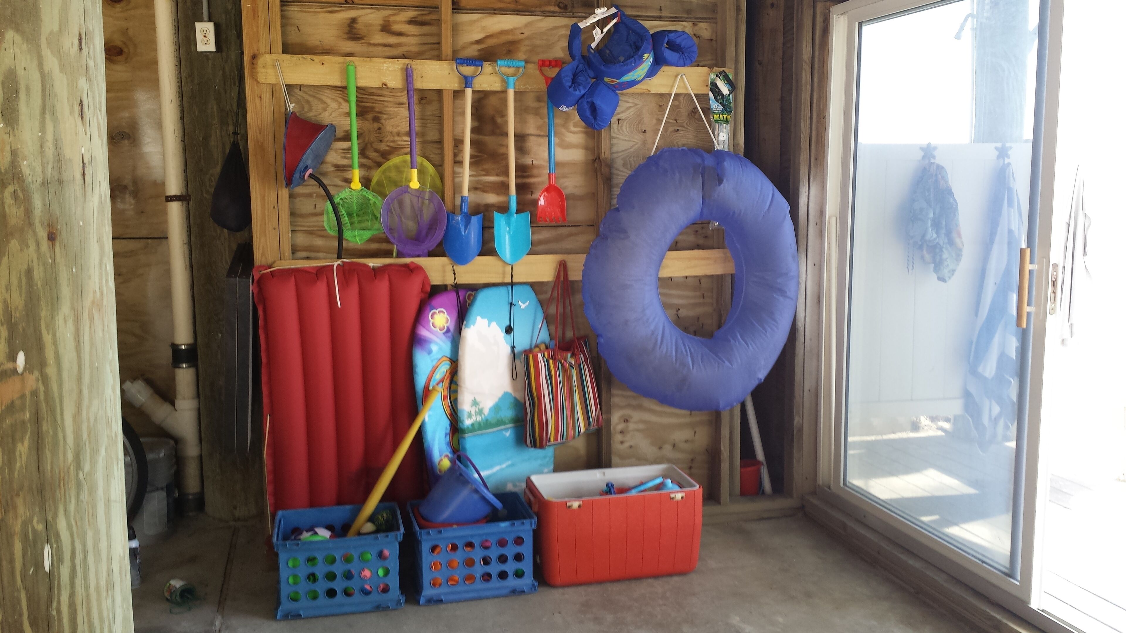 A storage room with various items like a blue inflatable ring, colorful bags, and cleaning tools.