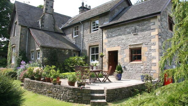 A stone house with a patio, outdoor seating, and a garden.