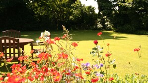 A garden with a wooden bench and table, surrounded by various flowers.