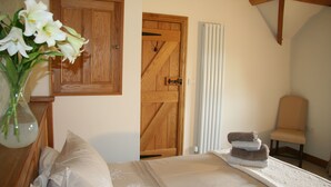 A bedroom with a wooden door, a chair, and a bed with a white bedspread.