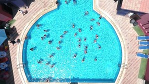 Une grande piscine extérieure entourée d’une terrasse carrelée.