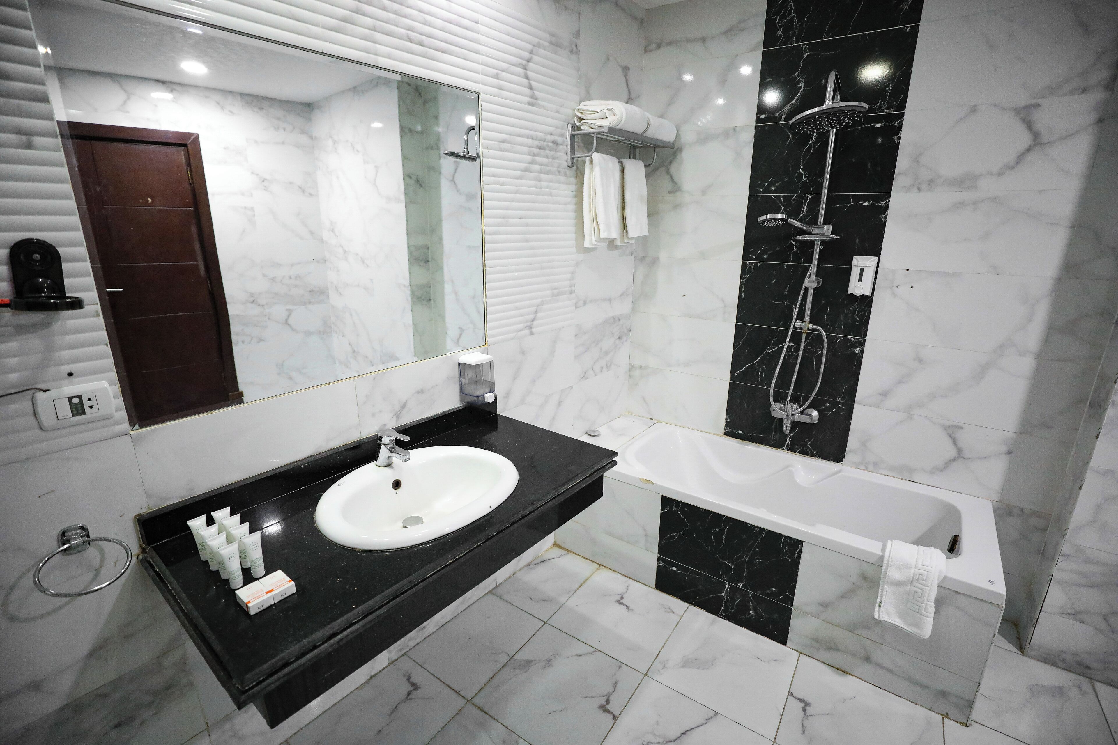 Un baño moderno con lavamanos de encimera negro, bañera blanca y ducha con mampara de vidrio.