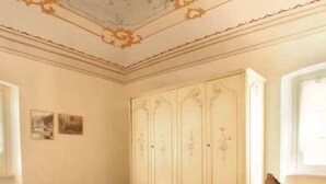 A bedroom with a bed, a wardrobe, and a chair. - I Fiori di Miranda (Casarza Ligure)