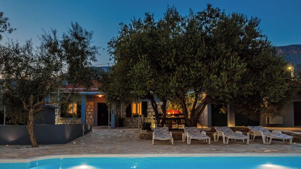 A pool area with lounge chairs and a building in the background. - Luxury villa complex Pendolino with heated pool and jacuzzi (Kastela)
