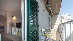 A balcony with a TV, a plant, and a dining area with chairs and a table. - Exclusive apartment in center with amazing view! (Split)