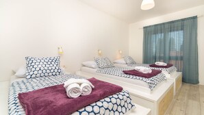 A hotel room with two beds, each with a patterned bedspread, pillows, and rolled towels. There is a window with curtains and a pendant light above the beds. - Exclusive apartment in center with amazing view! (Split)