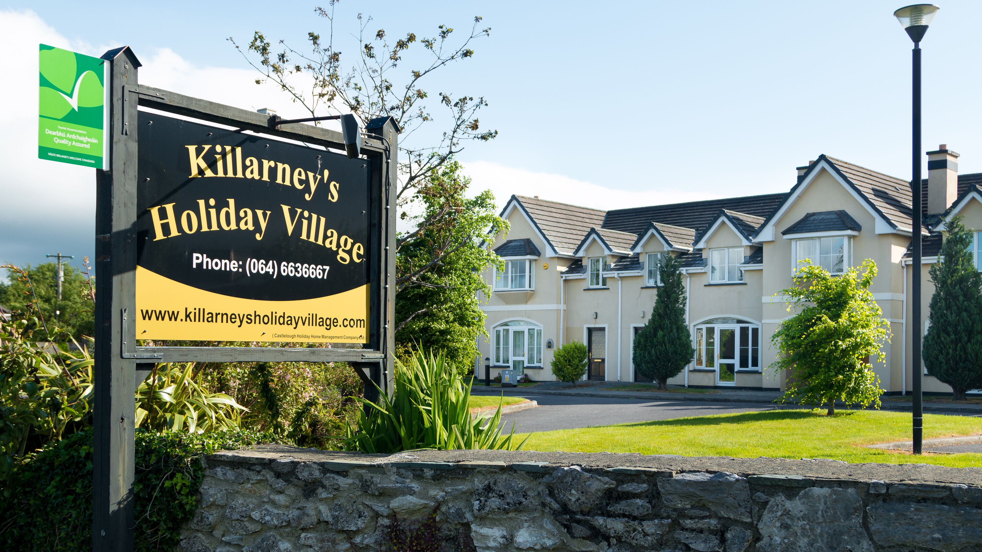 A sign for Killarney's Holiday Village with contact details and a website URL.