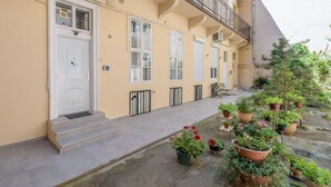 A building with a white door, multiple windows, and a balcony with railings. There are potted plants and steps leading to the entrance. - happy home Budapest BLUE (Budapest)