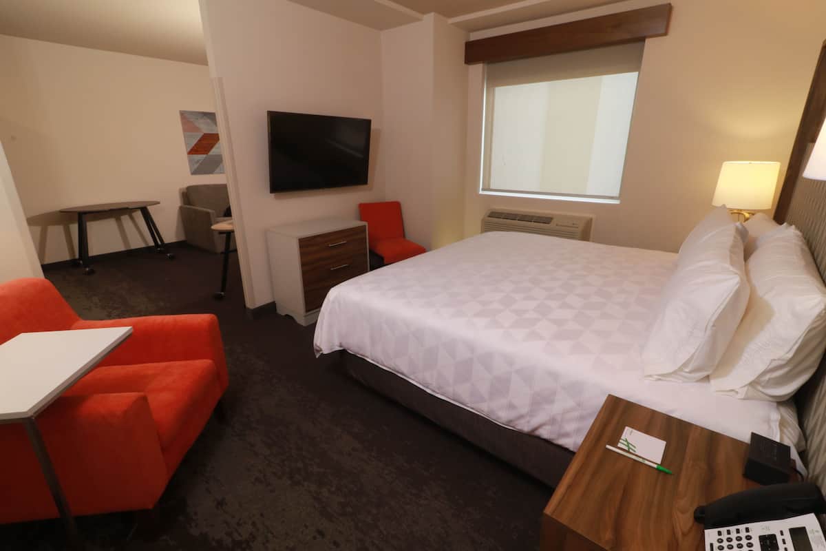 A hotel room with a bed, a desk, a chair, a TV, and a window.