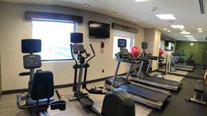 Uma academia com esteiras, elípticos e bolas de exercício.