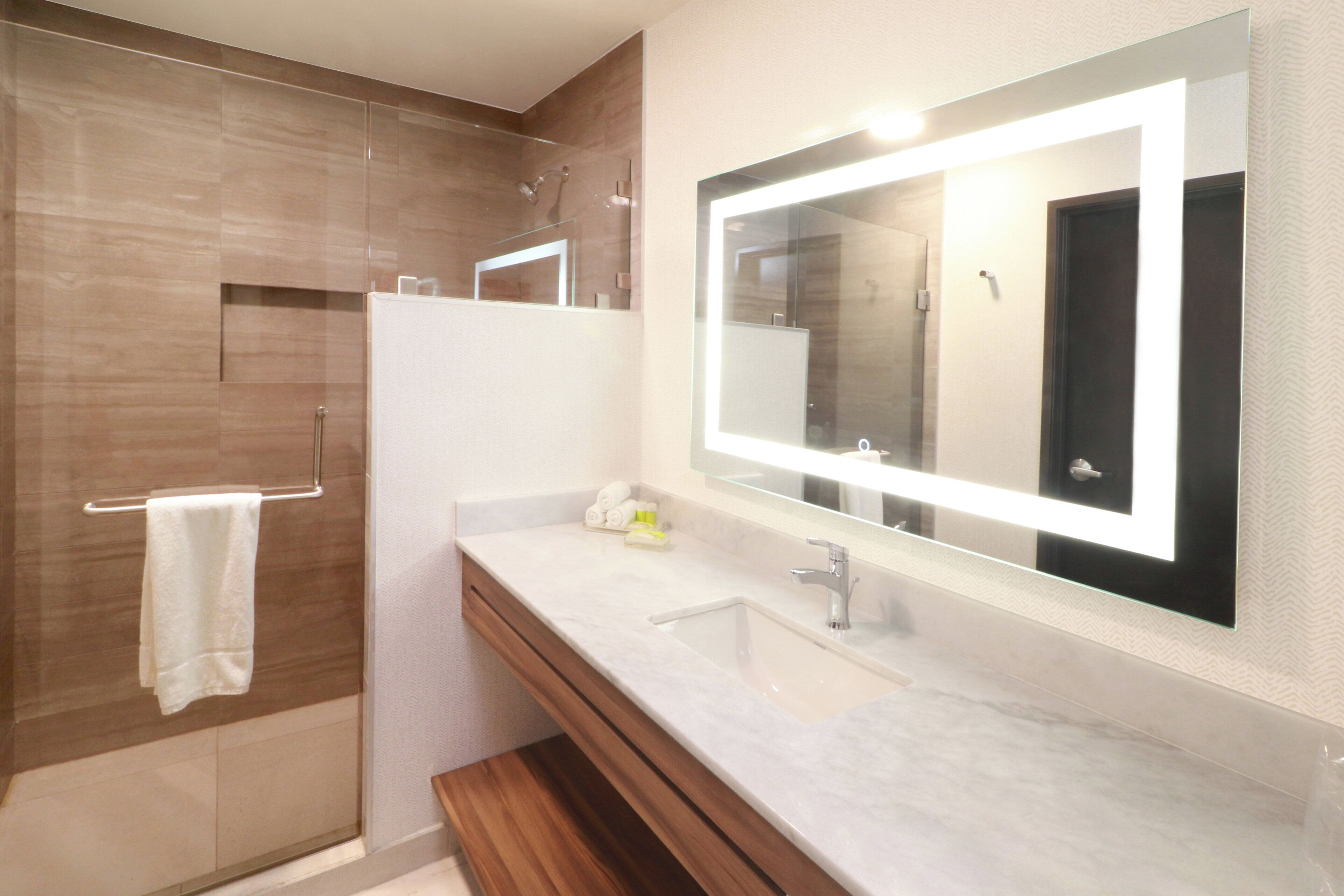 Un bagno moderno con un ampio specchio, un lavandino e una zona doccia.
