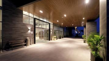 Un edificio moderno con techo de madera, puertas de vidrio y un banco.