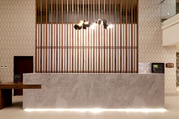 A reception desk with a marble top, vertical wooden slats, and a hanging light fixture. - Holiday Inn Hotel & Suites Monterrey Apodaca Zona Airport by IHG (Apodaca)
