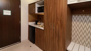 Cozinha compacta com armários de madeira, micro-ondas e cafeteira.