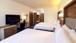 Quarto de hotel com duas camas, uma escrivaninha com cadeira, televisão e guarda-roupa.