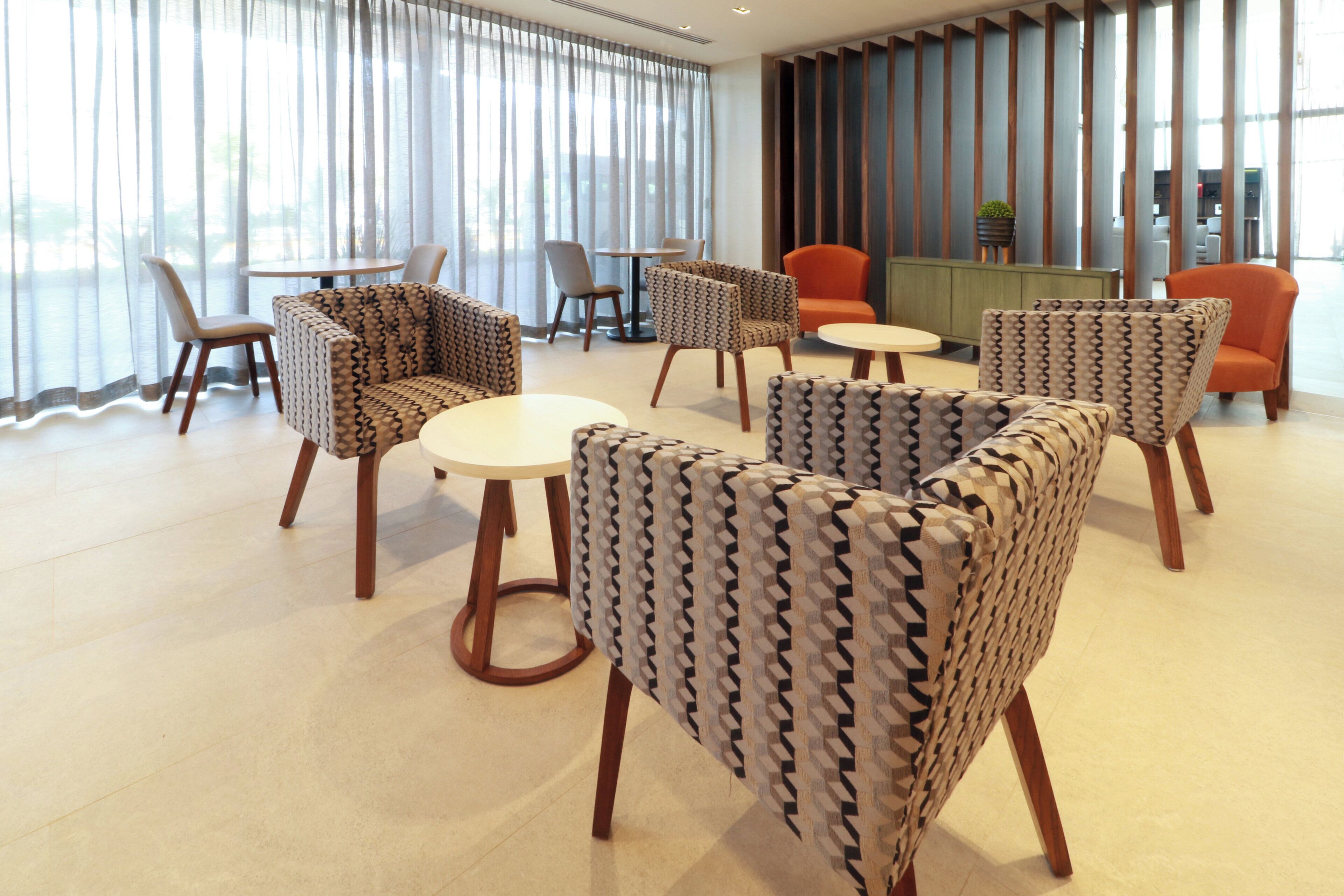 Un moderno vestíbulo de hotel con sillones estampados, una mesa redonda y una recepción.