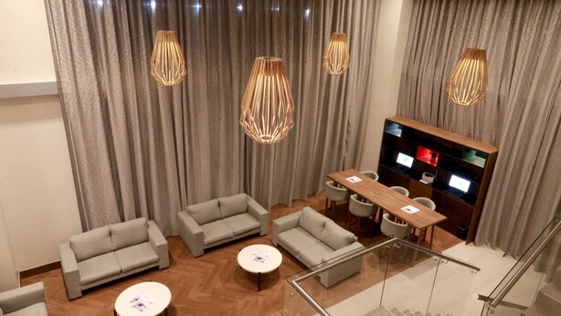 Uma sala de estar moderna com sofás cinza, uma mesa de centro de madeira e uma TV sobre um móvel de madeira.