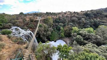 Un puente colgante sobre un río, con montañas al fondo.