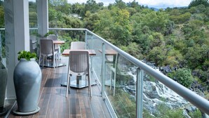A balcony with a glass railing overlooking a forested area and a waterfall. - Holiday Inn Tlaxcala by IHG (Yauhquemehcan)