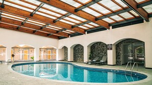 An indoor swimming pool with a wooden ceiling and stone walls. - Holiday Inn Tlaxcala by IHG (Yauhquemehcan)