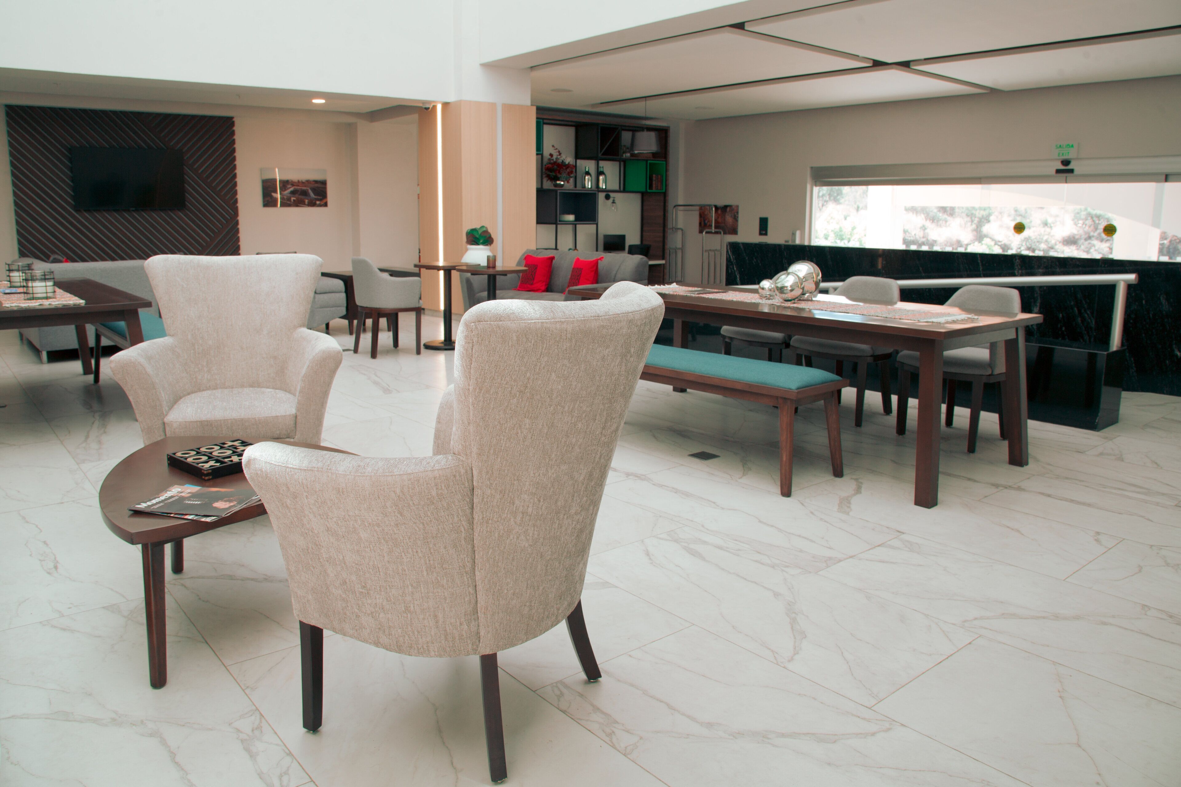 Een ruime woonkamer met een eettafel, twee fauteuils en een bank.