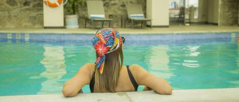 A pool area with a stone wall, lounge chairs, and a lifebuoy.