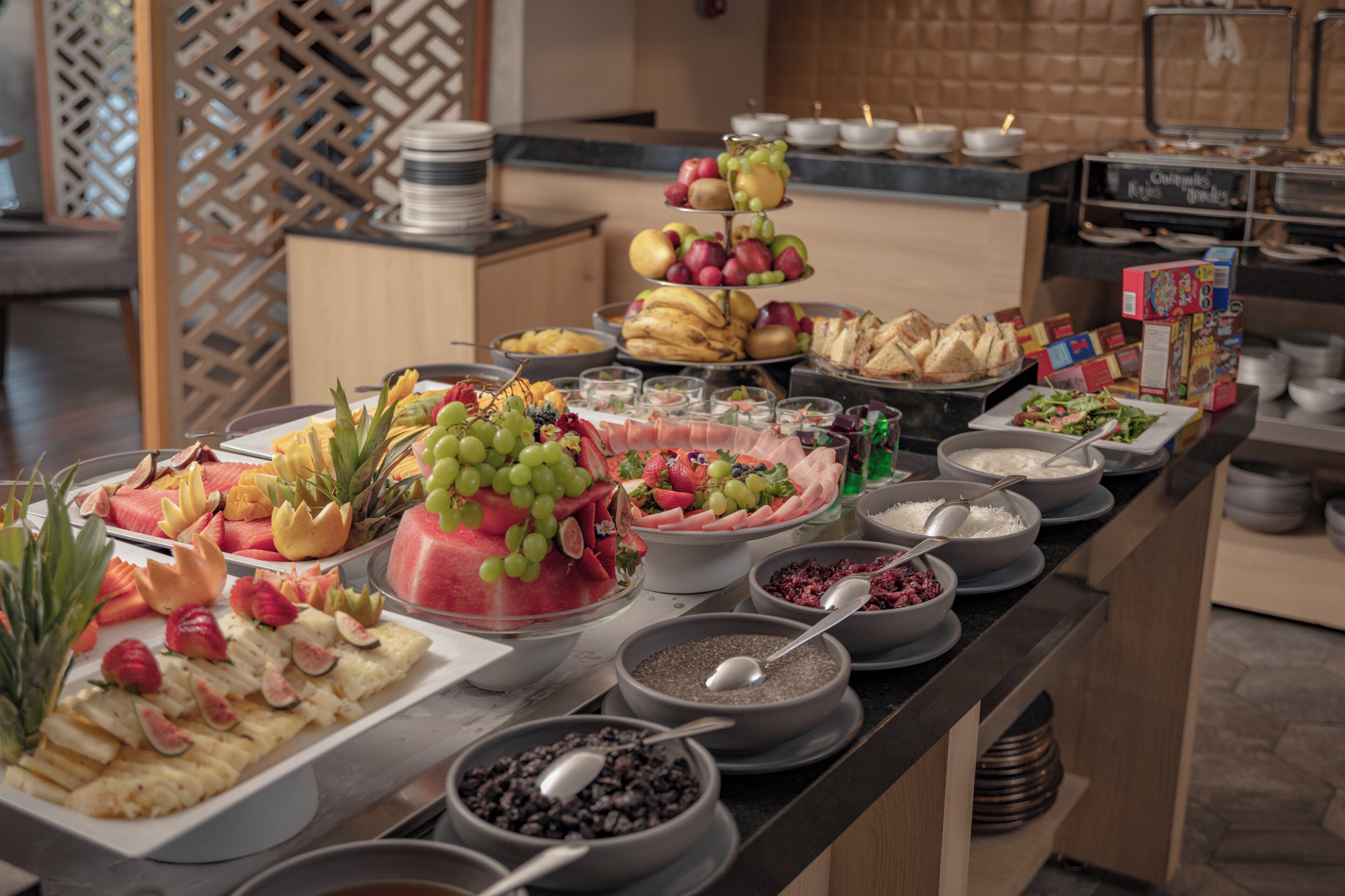 A buffet with various food items including fruits, cheeses, and breads.