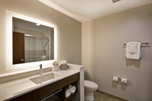 A modern bathroom with a large mirror, a sink, a toilet, and neatly arranged towels.