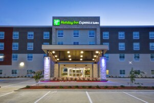 Edificio de Holiday Inn Express & Suites con fachada moderna, acceso cubierto y estacionamiento.