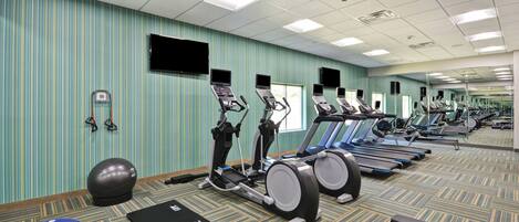 A gym with treadmills, exercise balls, and a mirrored wall.