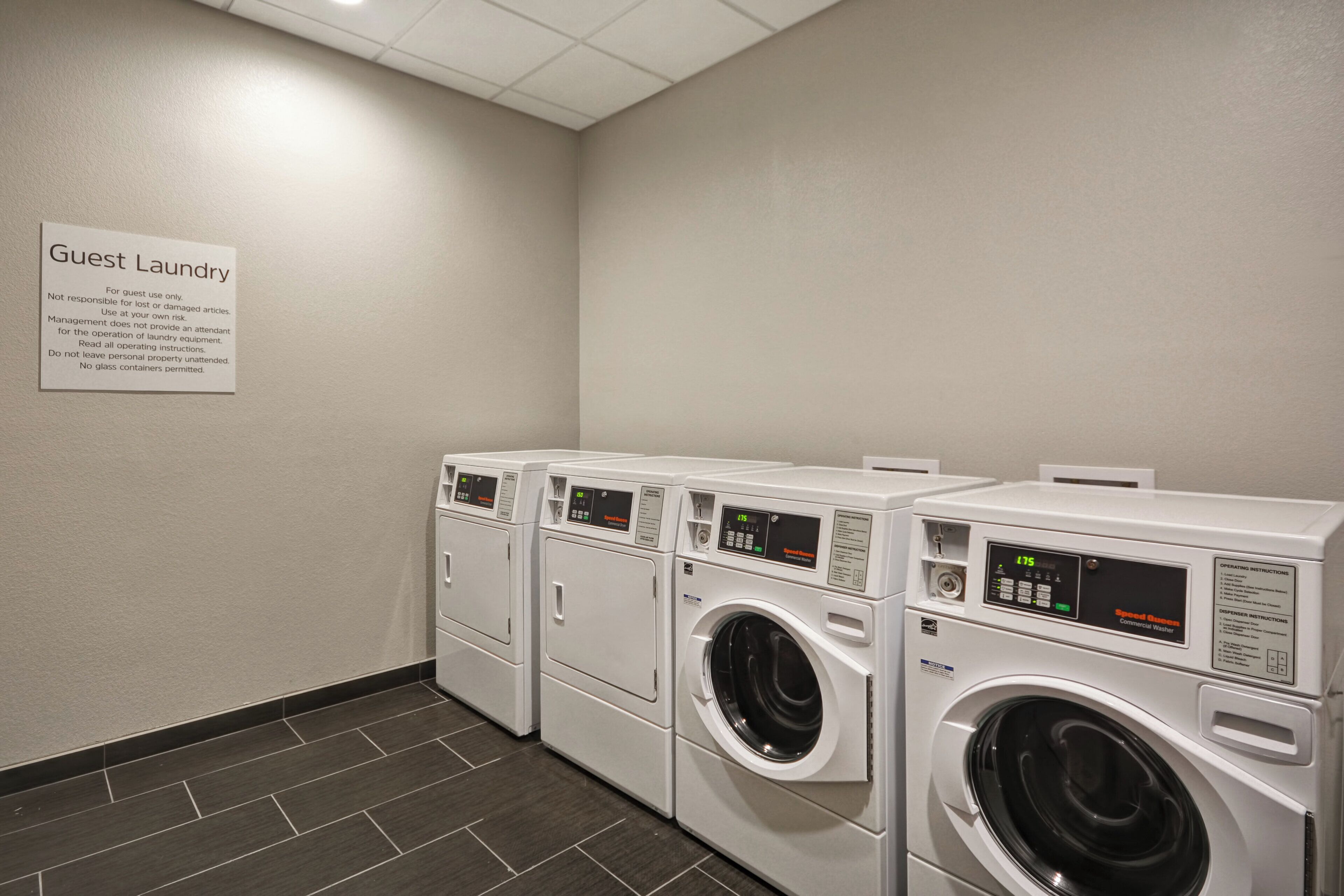 A guest laundry area with multiple washing machines and a sign with usage instructions.