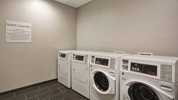 A guest laundry area with multiple washing machines and a sign with usage instructions.