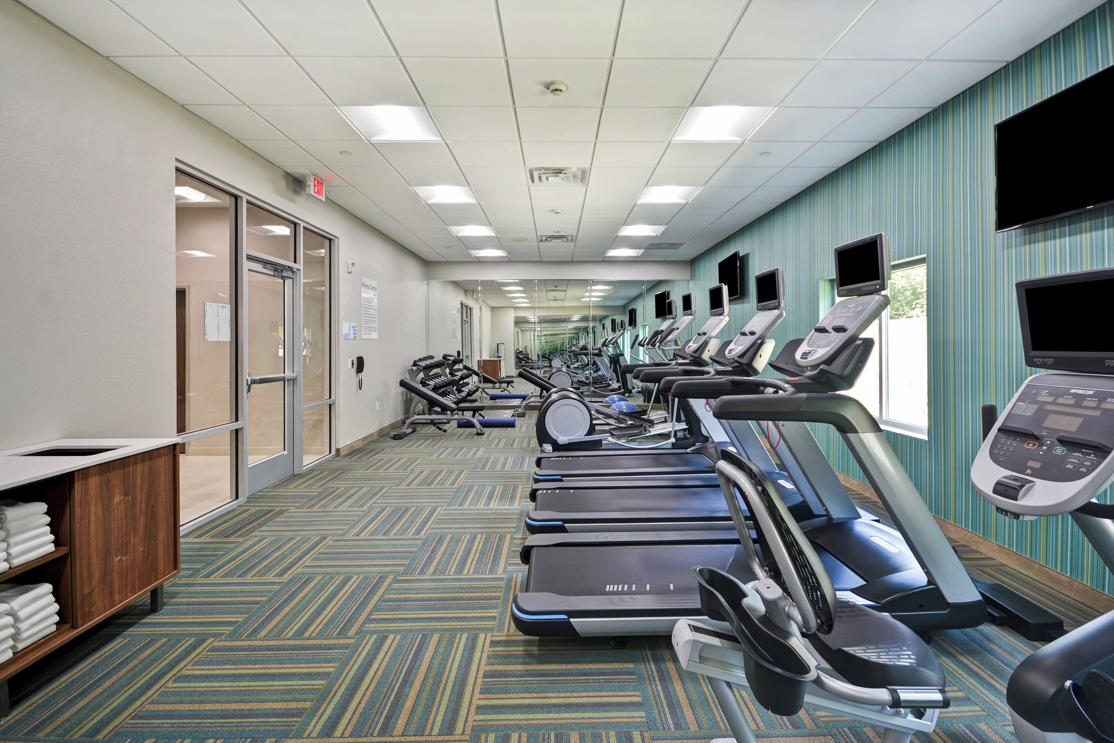 A gym with treadmills, exercise equipment, and a carpeted floor.