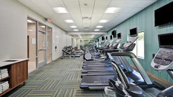 A gym with treadmills, exercise equipment, and a carpeted floor.