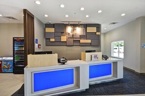 A hotel reception desk with a modern design, a Coca-Cola refrigerator, and a Nestlé ice cream machine. - Holiday Inn Express & Suites Houston NASA - Boardwalk Area by IHG (Seabrook)