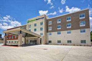 Edificio de Holiday Inn Express & Suites con entrada cubierta, múltiples ventanas y cielo despejado.