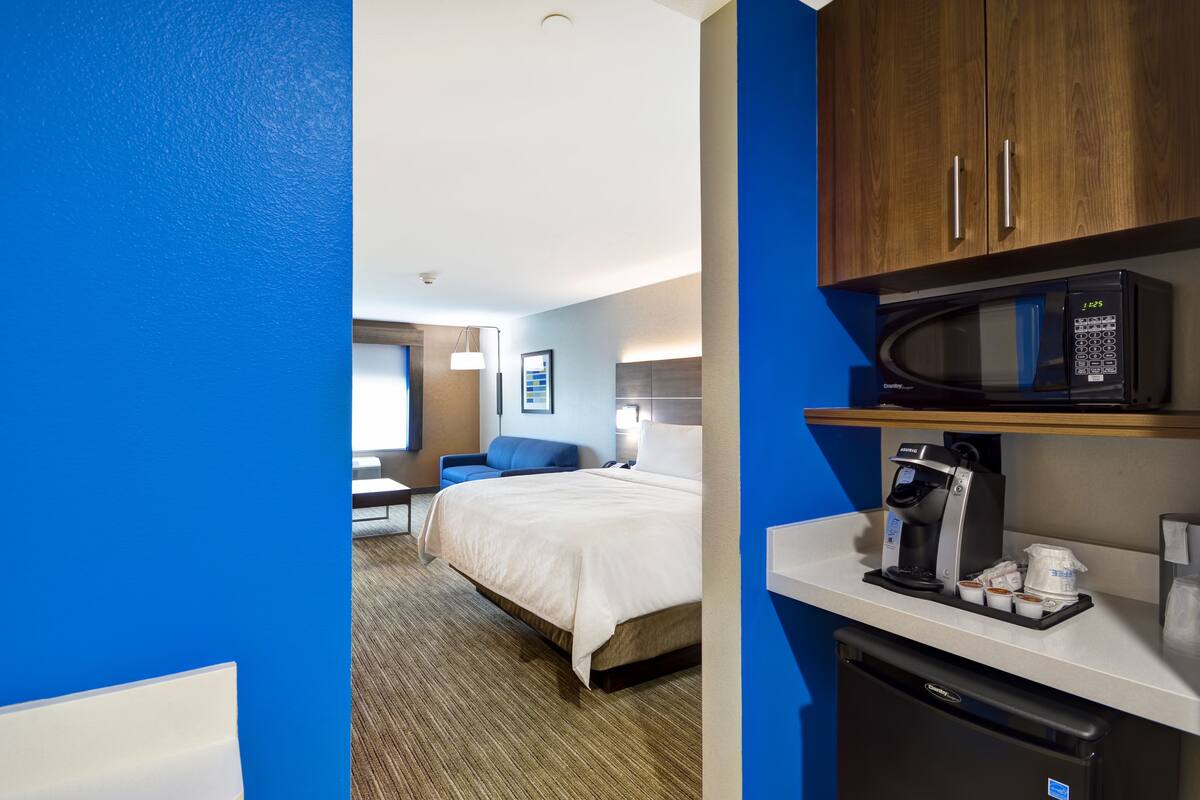 A hotel room with a bed, a desk, a microwave, and a coffee maker.