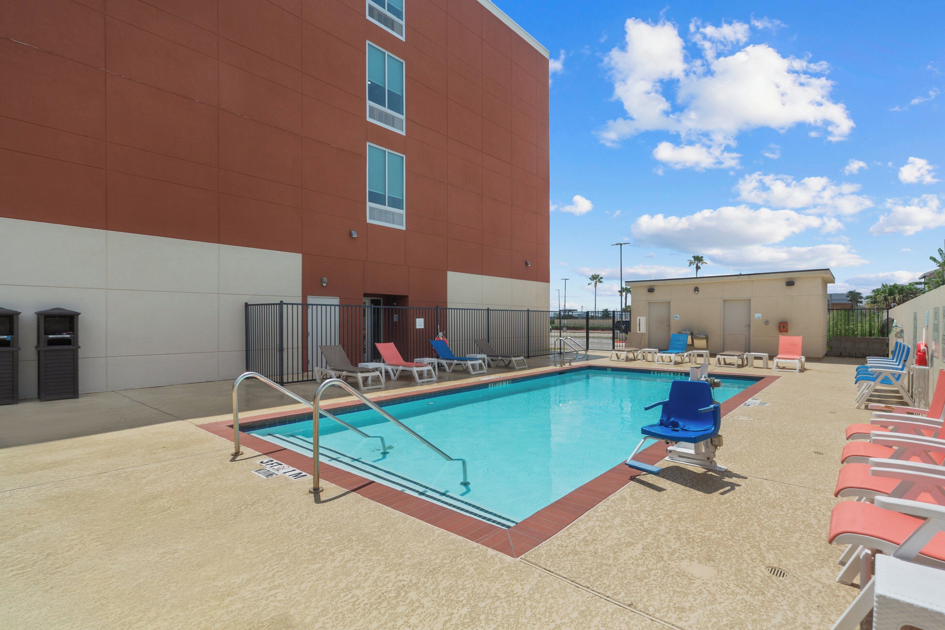 A swimming pool with lounge chairs and a building in the background.