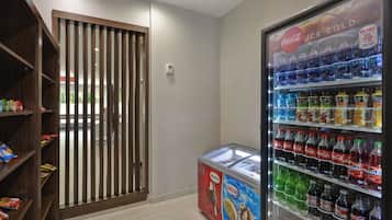 A vending machine with various beverages and a freezer with ice cream.