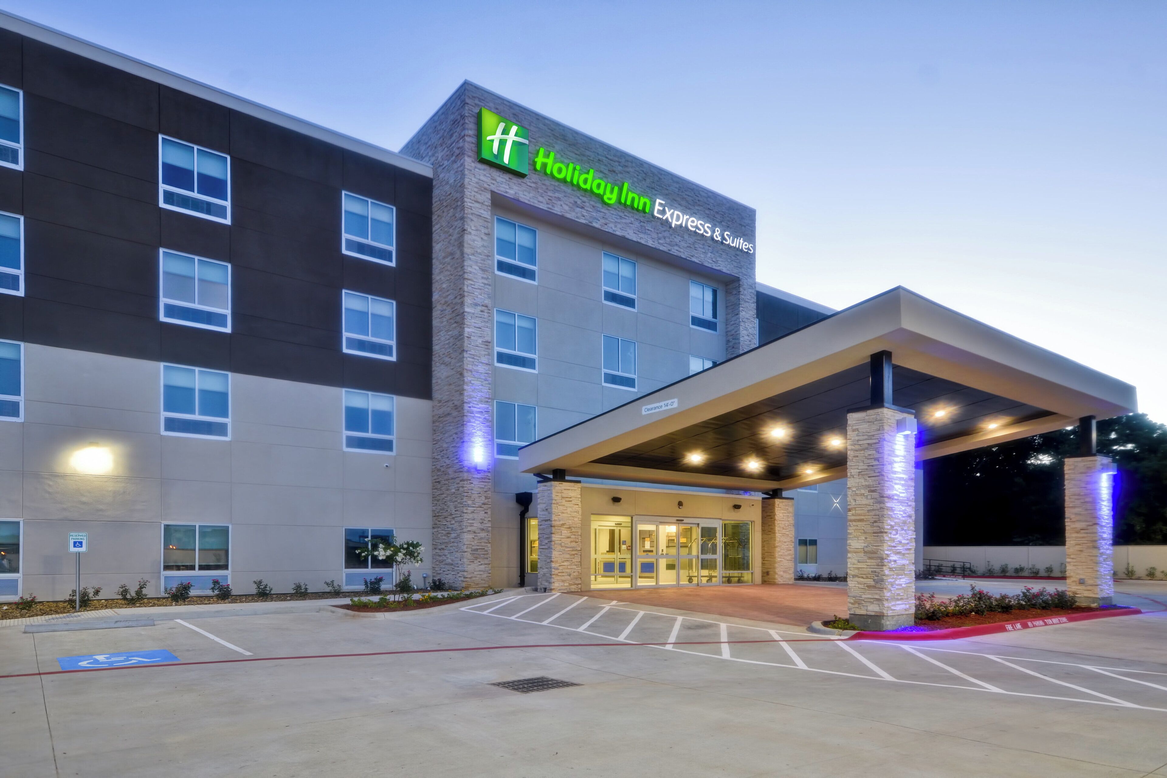 A Holiday Inn Express & Suites building with a covered entrance and a parking lot.