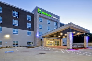 Edificio de Holiday Inn Express & Suites con entrada cubierta y estacionamiento.