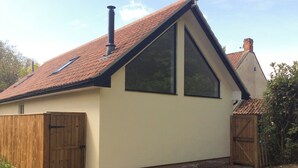 Een gelijkvloers huis met een schuin dak, een houten hek en een grindpad.