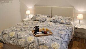 Een net opgemaakt bed met bloemenbeddengoed, twee bedlampjes en een dienblad met ontbijtartikelen.