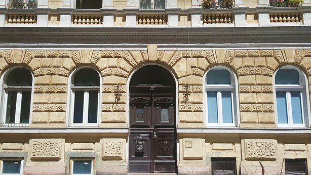 Un edificio con fachada simétrica, ventanas en arco y una entrada central con una puerta marcada con el número 43.