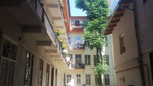 Un patio estrecho con varios balcones, algunos con plantas y flores.