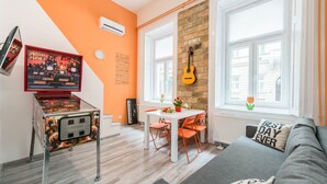 Una sala de estar moderna con un sofá, una mesa de comedor con sillas, un televisor y una guitarra en la pared.