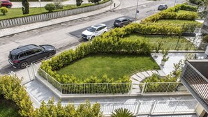 Un quartier résidentiel avec une route, une clôture blanche et de la verdure.