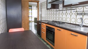 Une cuisine équipée d’une cuisinière, d’un four et d’un évier, avec des meubles de couleur orange et un plan de travail foncé.