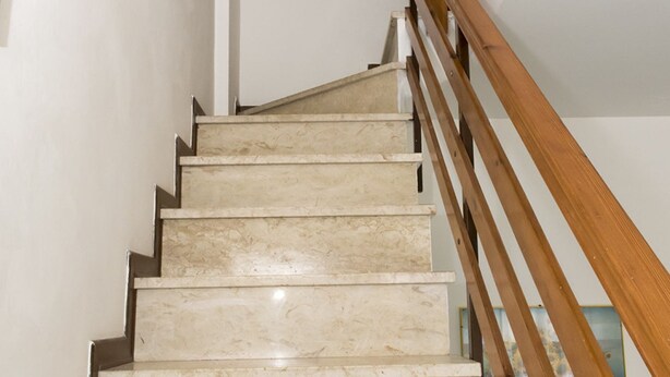 Un escalier avec des marches en marbre et une rampe en bois.