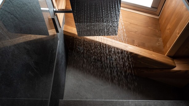 Ein modernes Interieur mit schrägverdeckter Decke, einer Holzbank und einem schwarzen, gepolsterten Sitzplatz.